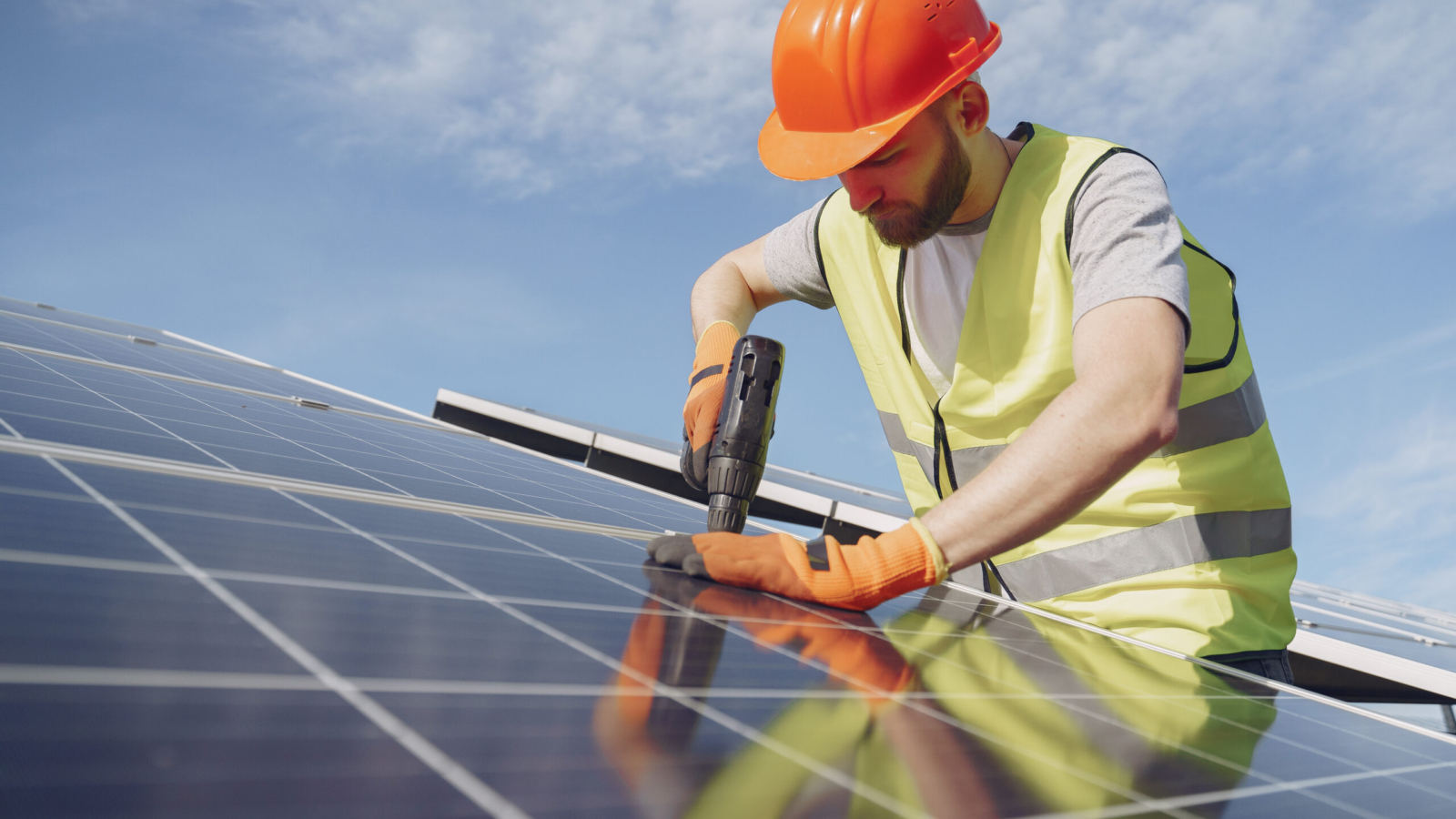 Male worker with solar batteries. Man in a protective helmet. Installing stand-alone solar panel system.