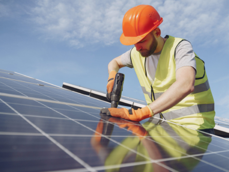 Male worker with solar batteries. Man in a protective helmet. Installing stand-alone solar panel system.